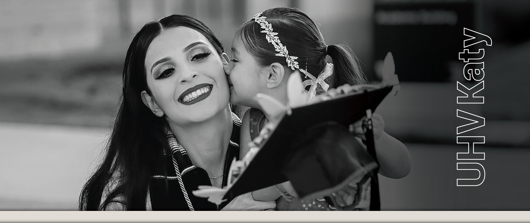 UH Katy graduate being kissed on her cheek by her young daughter